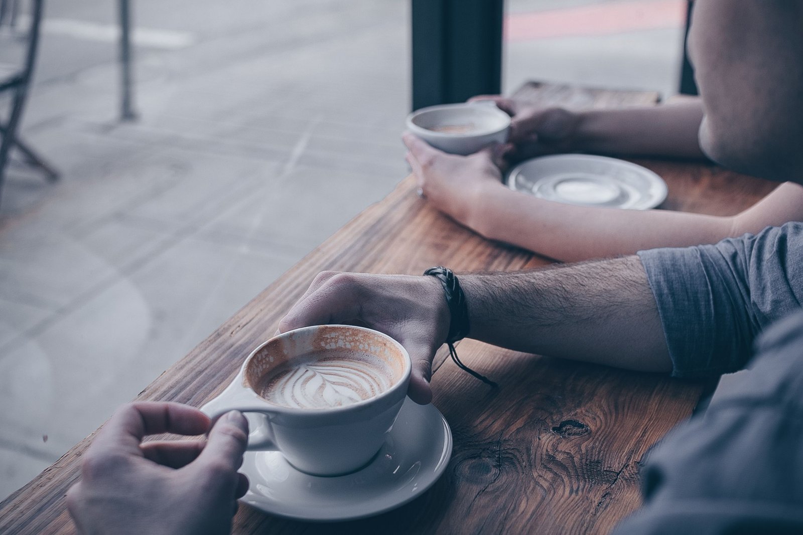 Two individuals relax with cups of coffee at a cozy cafe, creating a warm ambiance.